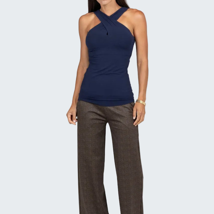 Woman wearing a navy halter top and brown pants on a gray background
