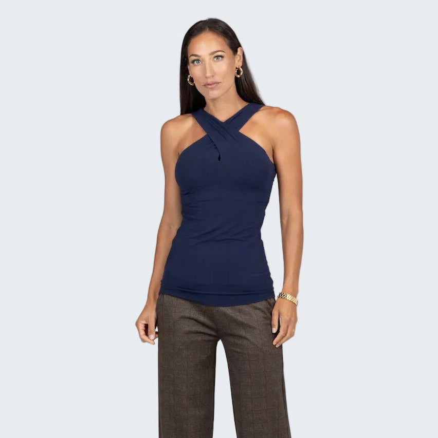 Woman wearing a navy halter top and brown pants on a gray background