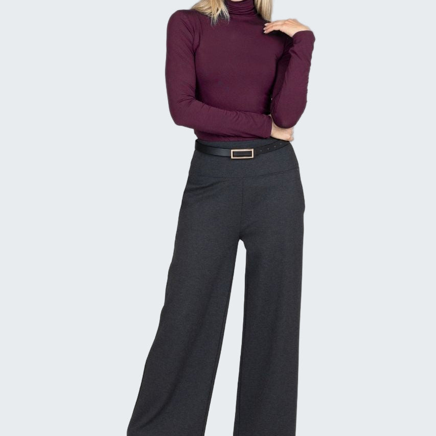 Woman wearing a purple turtleneck and black wide-leg pants on a white background