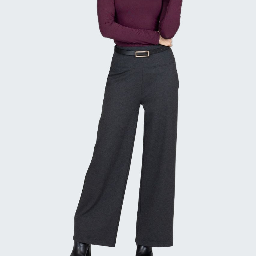 Woman wearing a purple turtleneck and black wide-leg pants on a white background