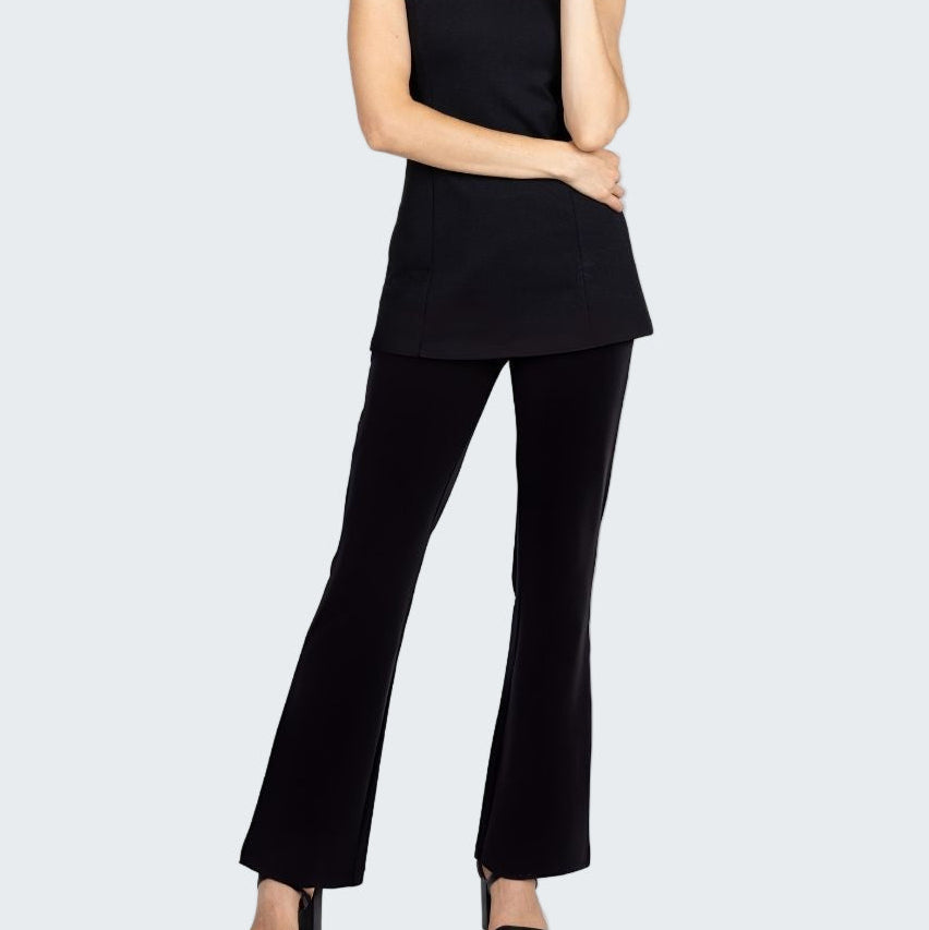 Woman wearing a black sleeveless top and black flared pants on a white background