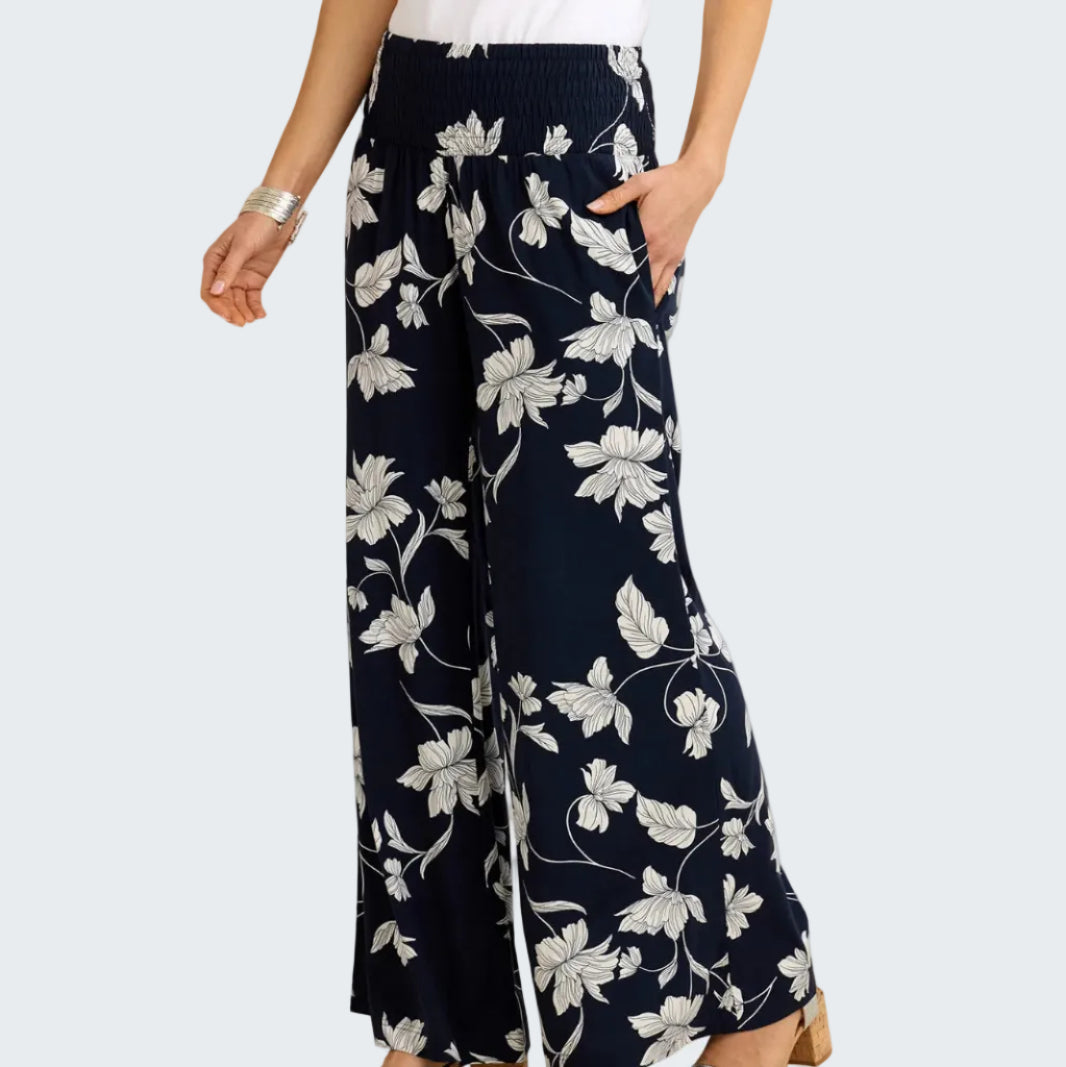 Navy blue pants with white floral pattern worn by a person on a beige background