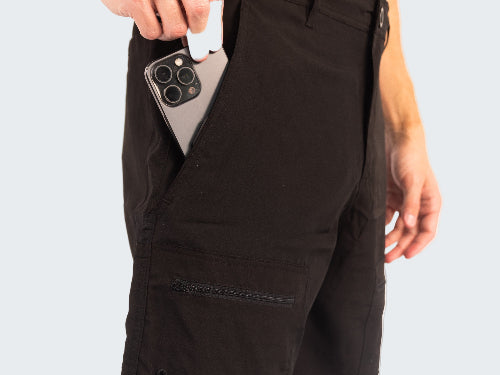 Person wearing black shorts holding a phone with a white background
