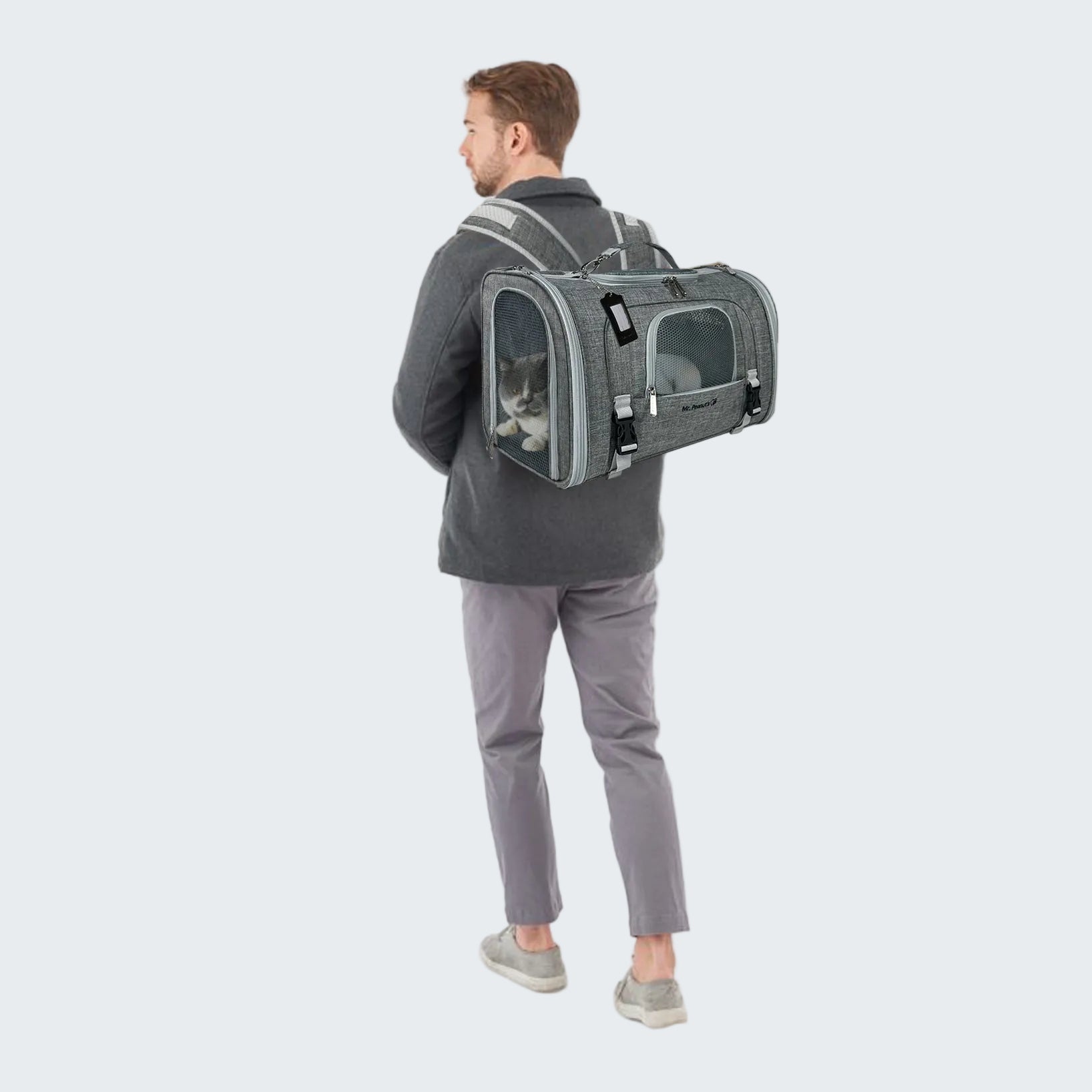 Person wearing a gray pet carrier backpack with a cat inside on a white background