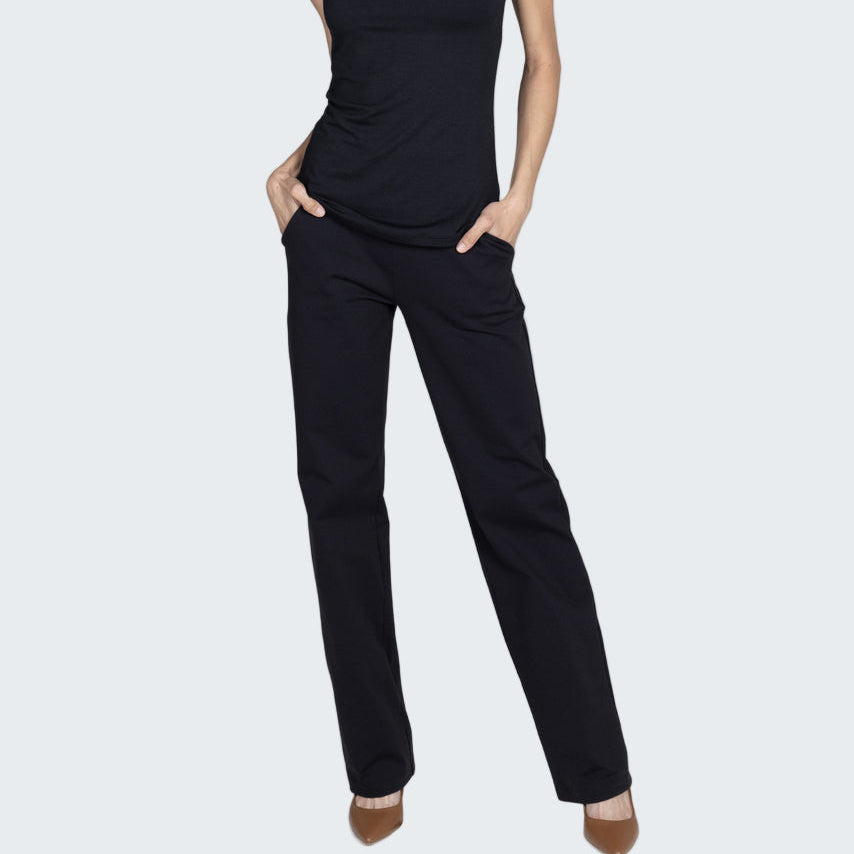 Woman wearing a black sleeveless top and pants on a gray background