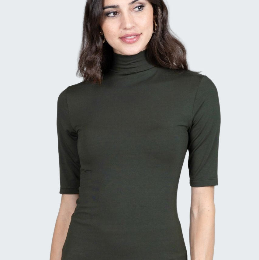 Woman wearing a green turtleneck shirt against a plain background