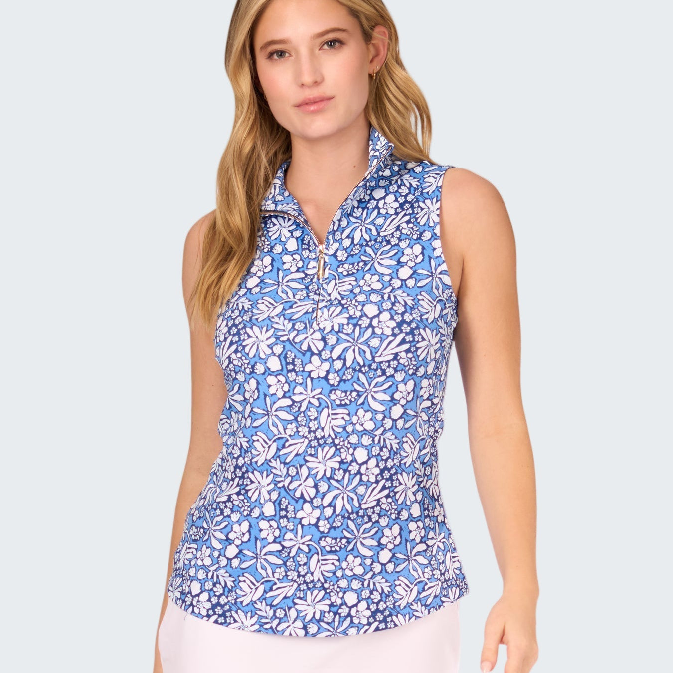 Woman wearing a blue floral sleeveless top and white skirt on a white background