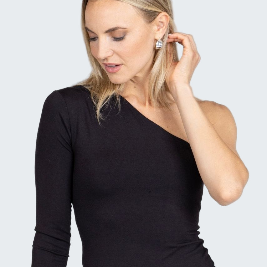 Woman wearing a black one-shoulder top against a plain background