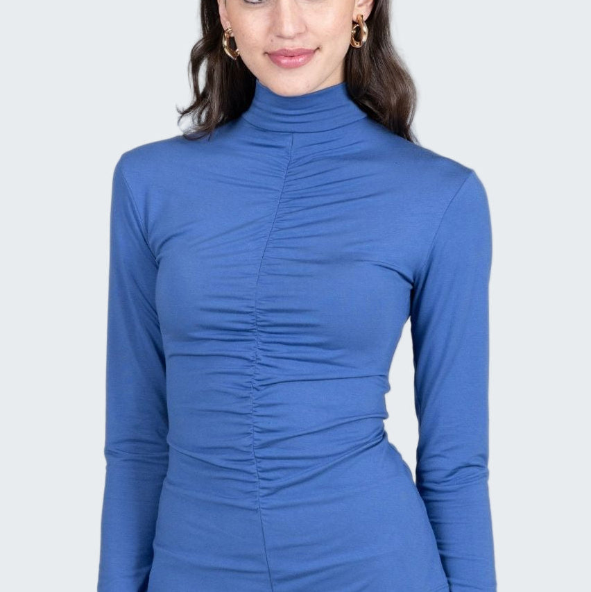 Woman wearing a blue long-sleeve top against a gray background