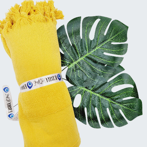 Yellow fabric roll with a green leaf on a white background