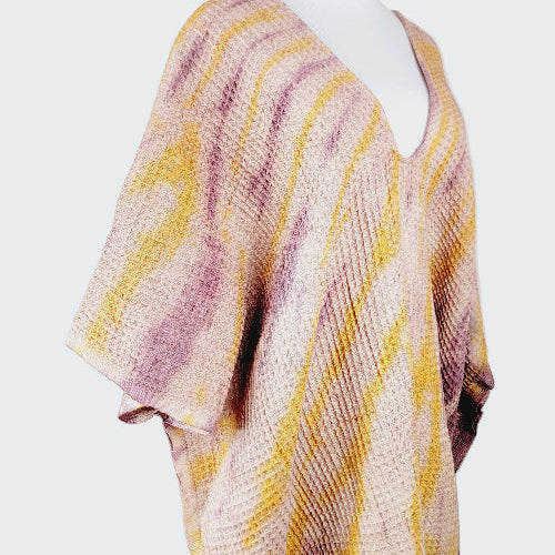 Mannequin wearing a pink and yellow patterned poncho against a plain background