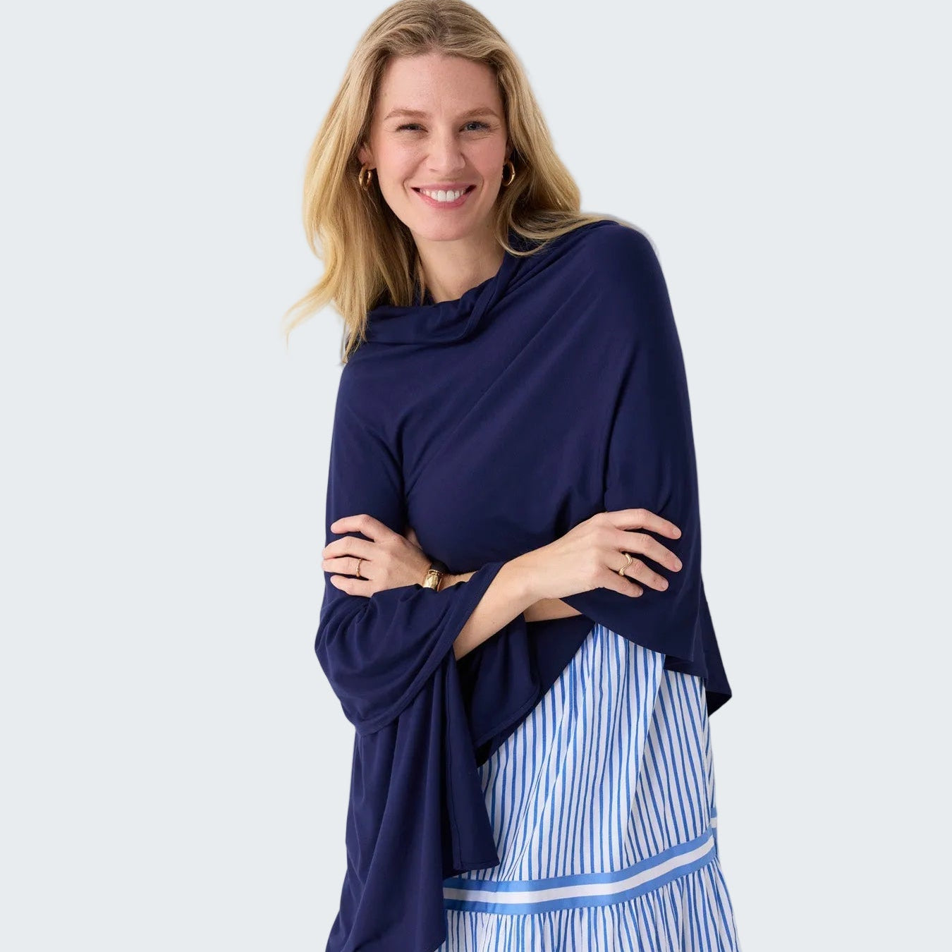 Woman wearing a navy blue top and blue and white striped pants against a white background