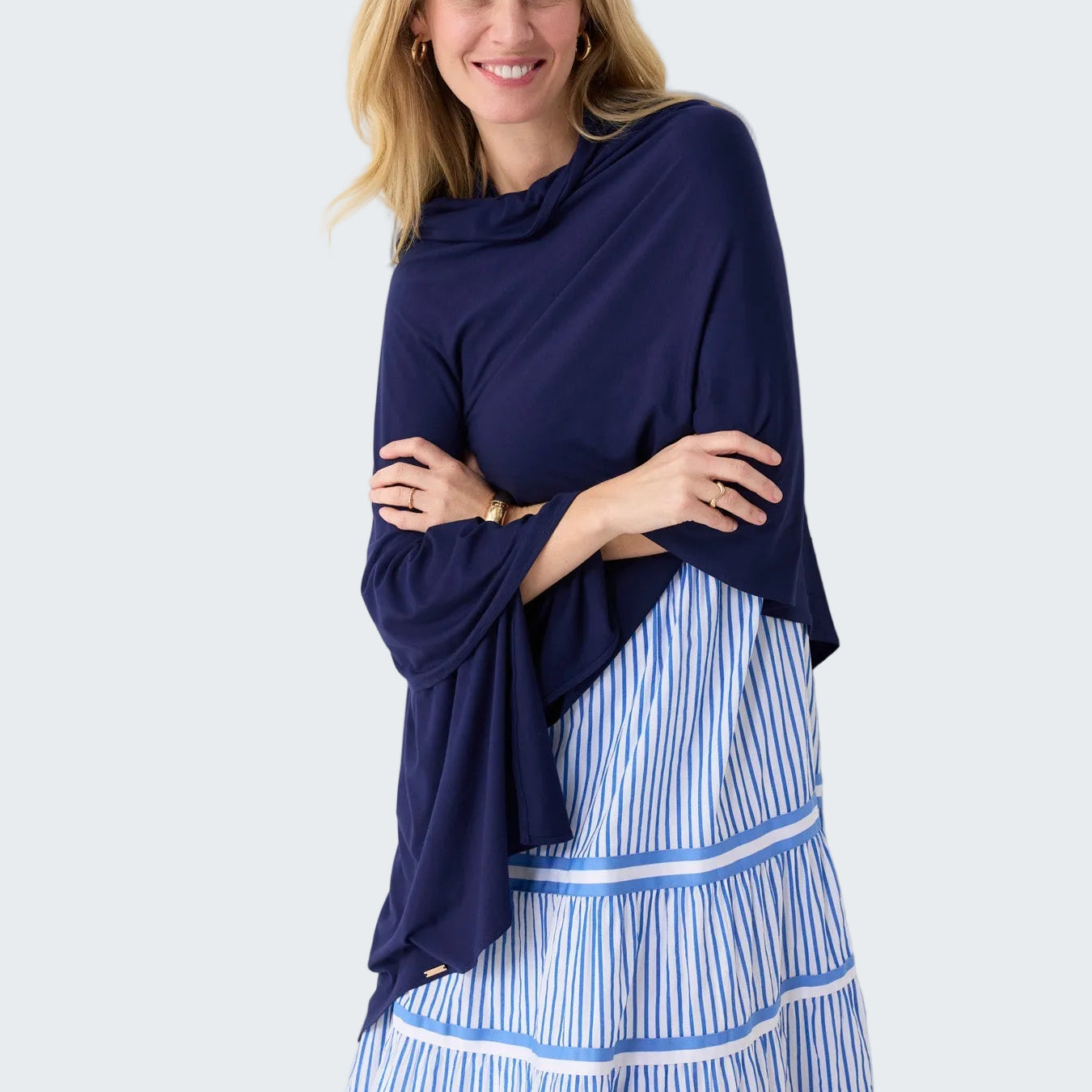 Woman wearing a navy blue top and blue and white striped pants against a white background