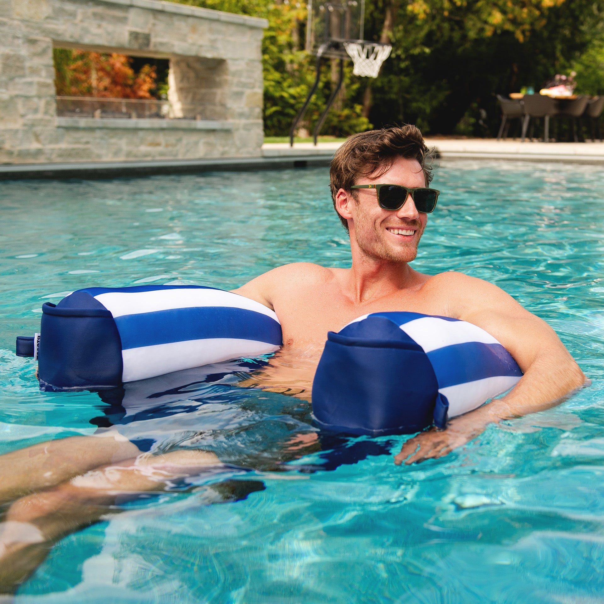 Man in a pool with blue and white striped arm floats