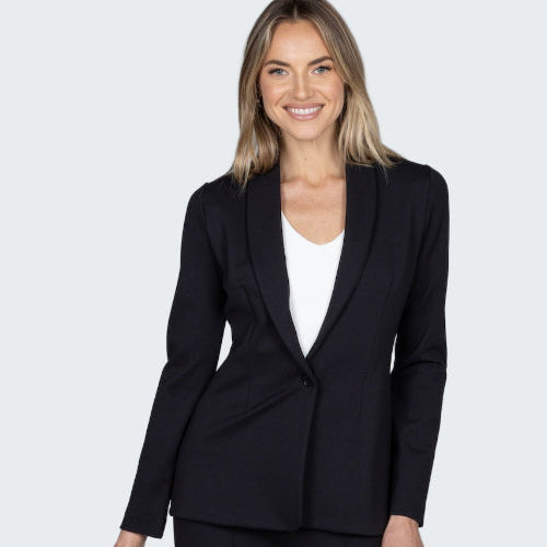Woman wearing a black suit jacket and pants on a gray background
