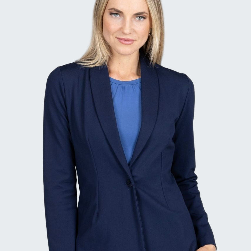 Woman wearing a navy blazer over a blue top on a gray background