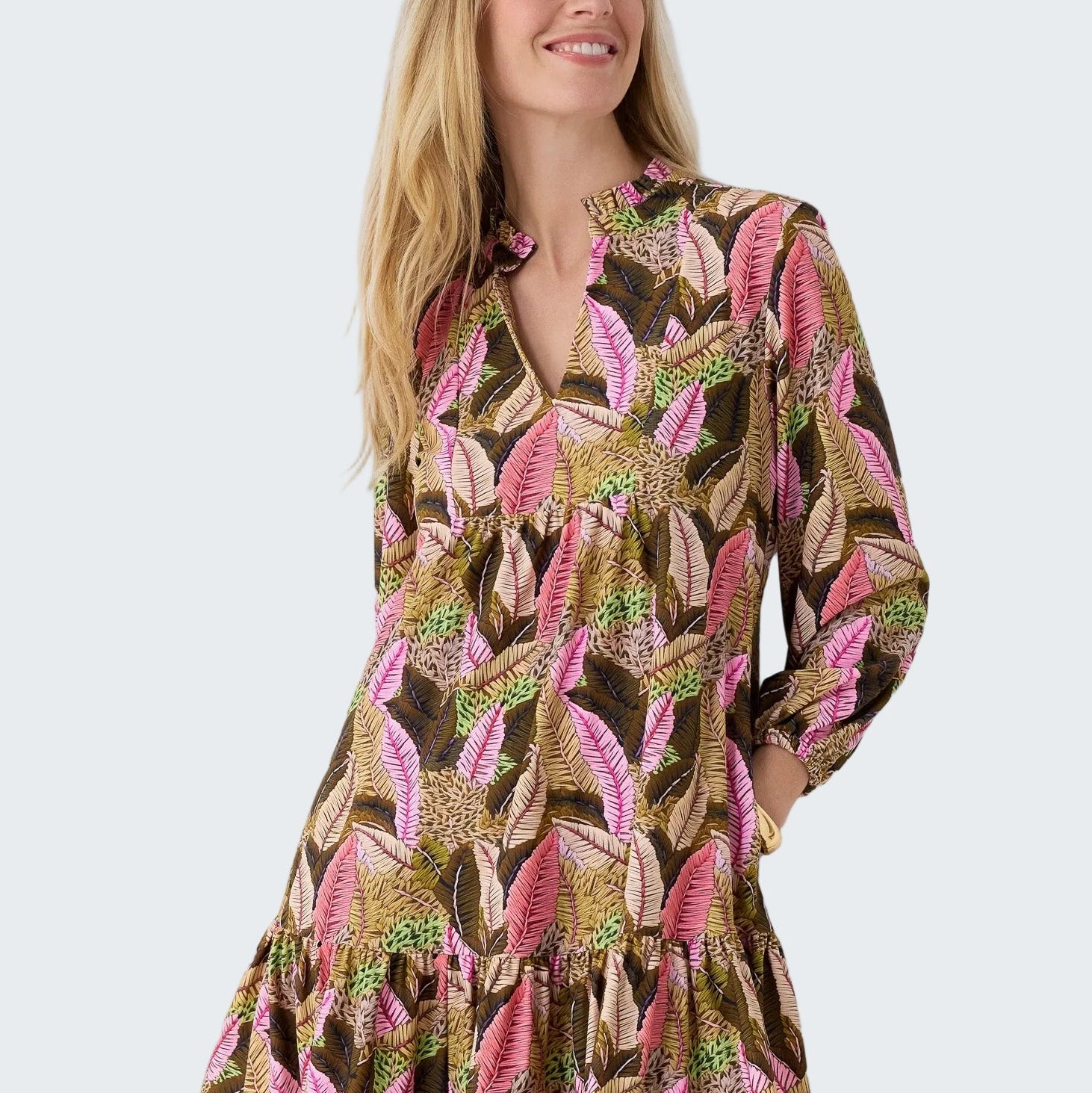 Woman wearing a patterned dress with long sleeves on a plain background