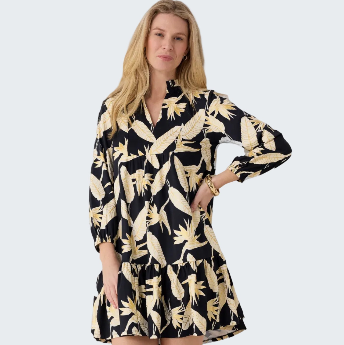 Woman wearing a black dress with gold floral pattern against a white background
