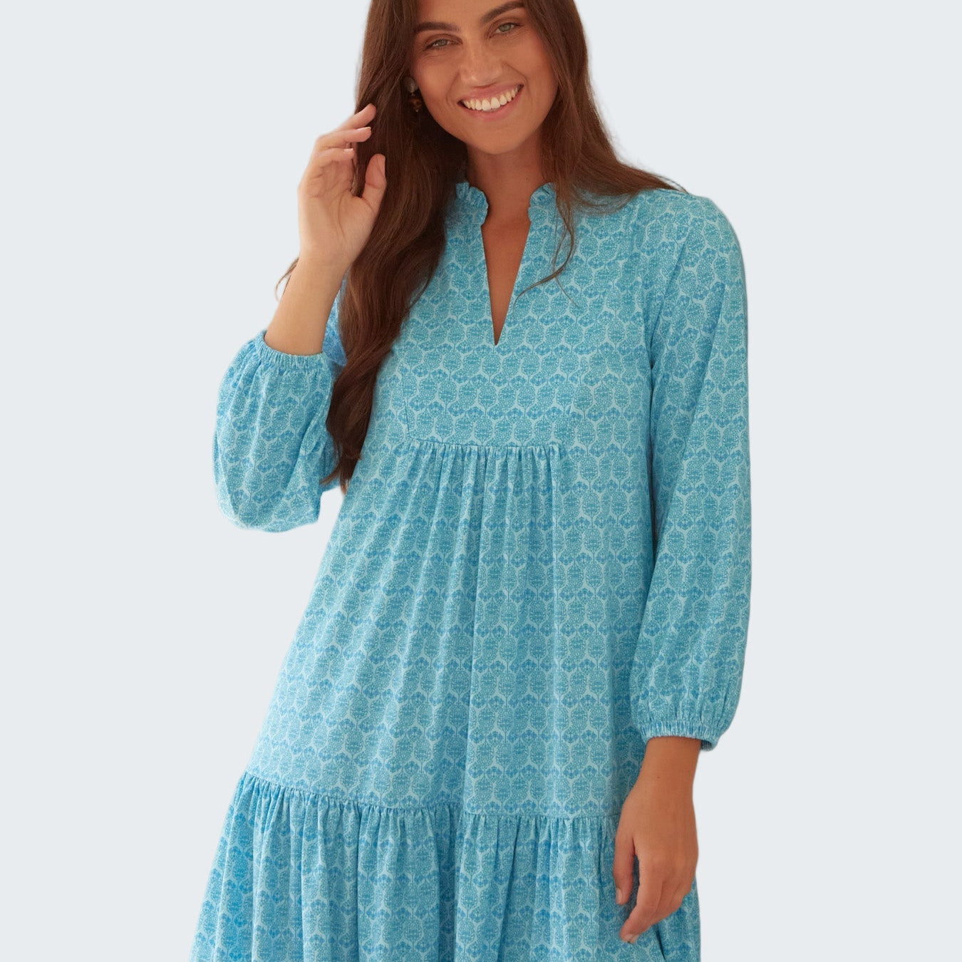 Woman wearing a blue patterned dress against a light background