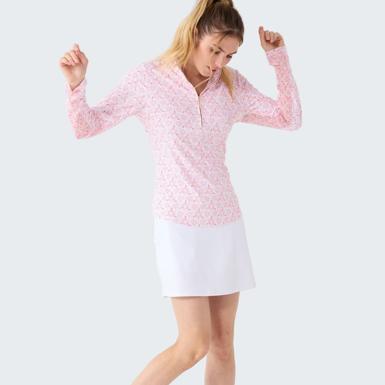 Woman wearing a pink long-sleeve top and white skirt on a white background