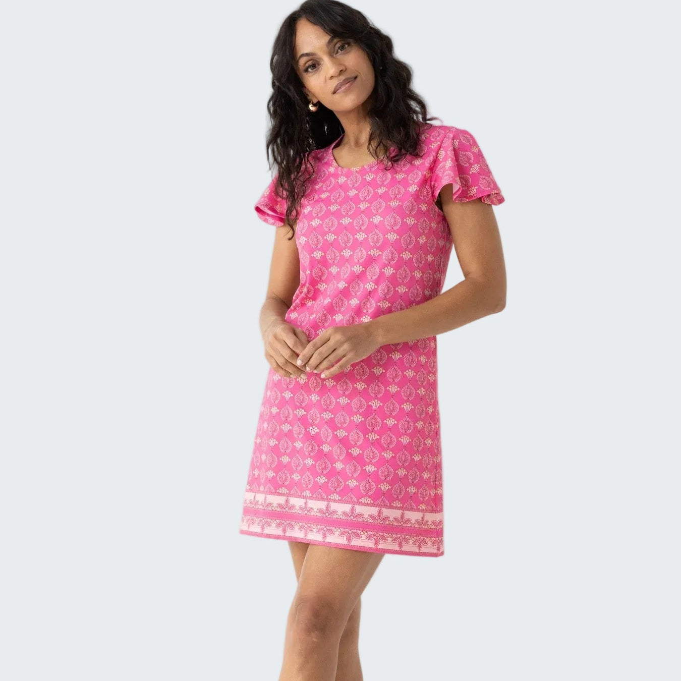 Woman wearing a pink dress with a white pattern on a white background