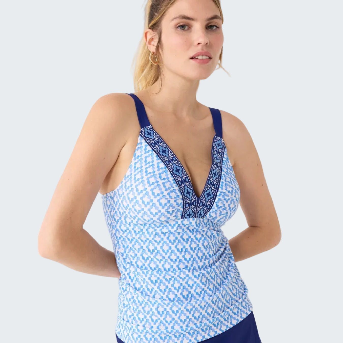 Woman wearing a blue and white patterned top with a plunging neckline on a white background