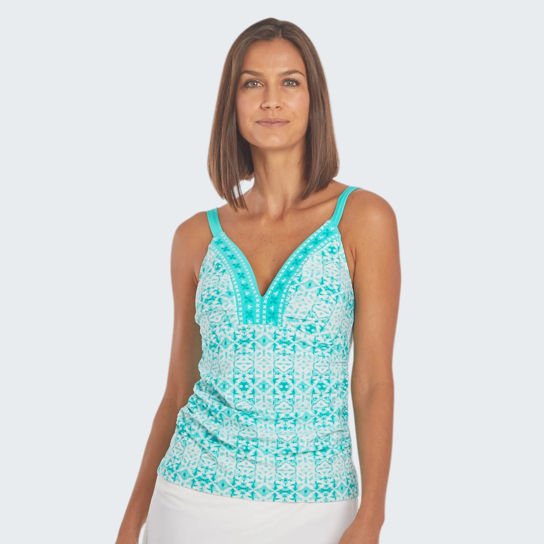 Woman wearing a turquoise patterned top and white skirt on a white background