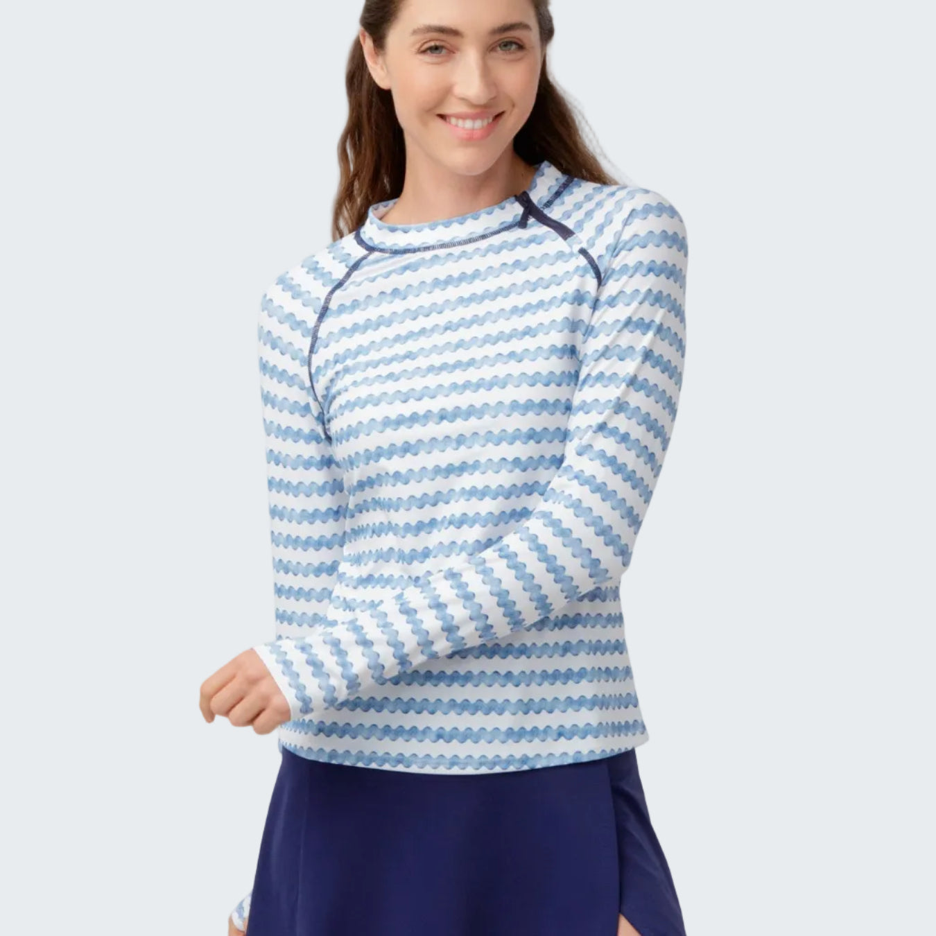 Woman wearing a blue and white striped long-sleeve top and navy skirt on a light gray background