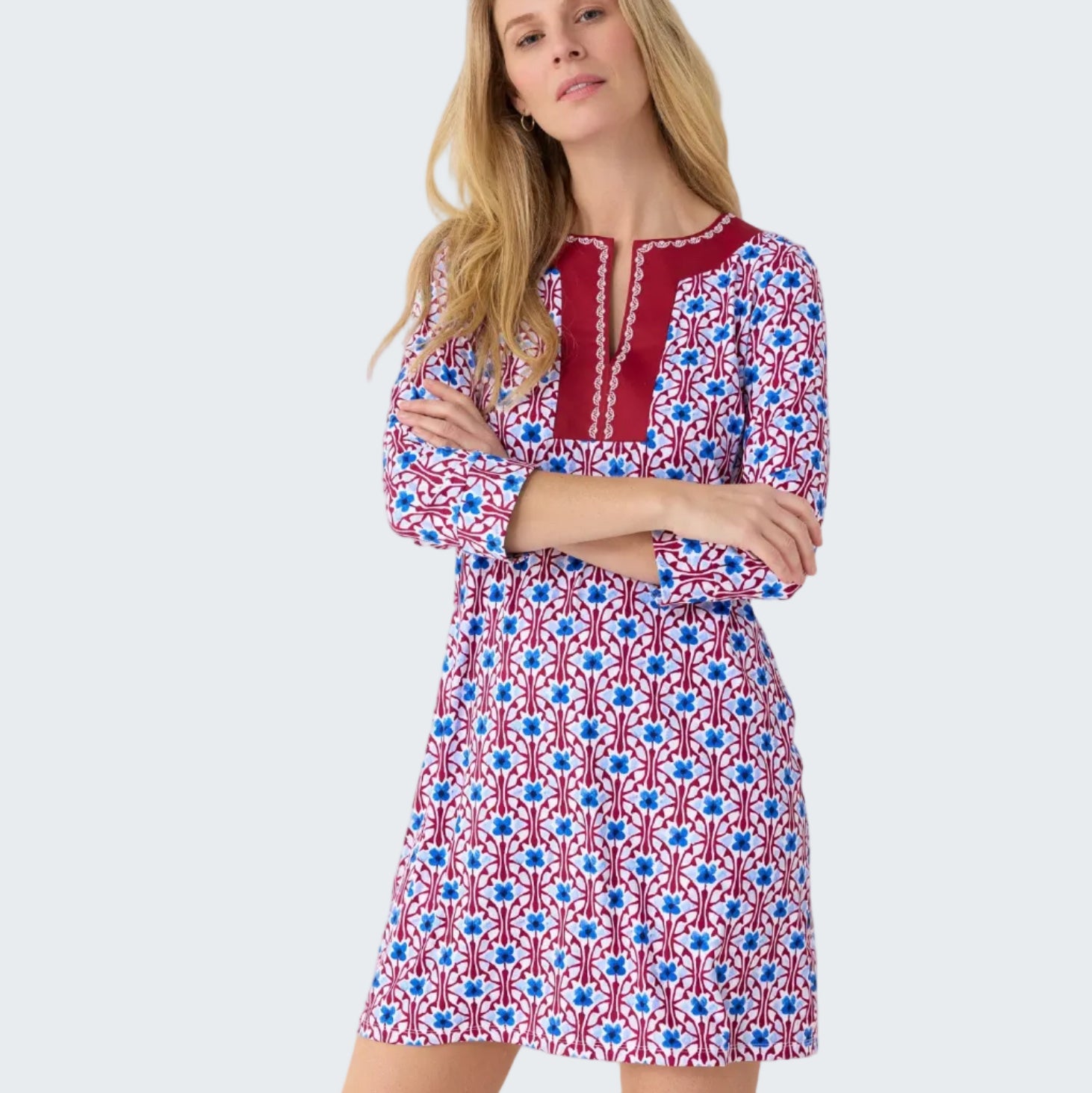 Woman wearing a patterned dress with red, white, and blue design on a plain background