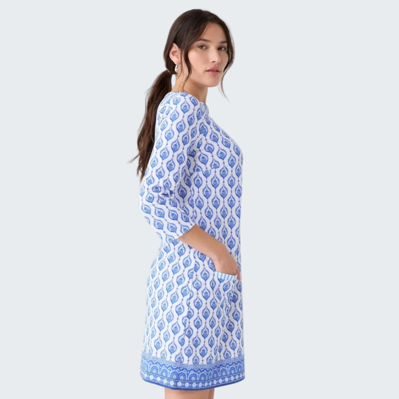 Woman wearing a blue and white patterned dress on a light gray background