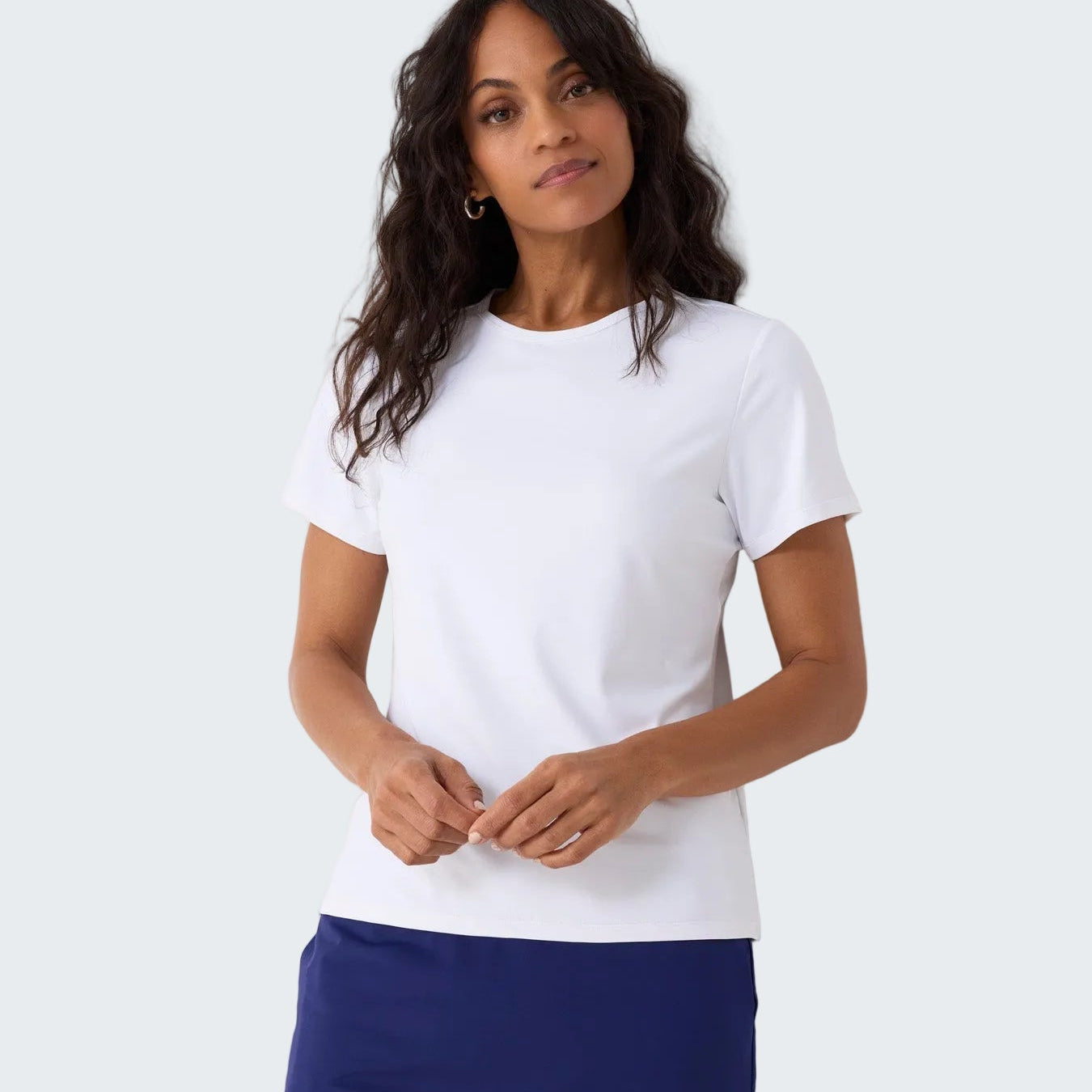 Woman wearing a white t-shirt and blue skirt against a white background