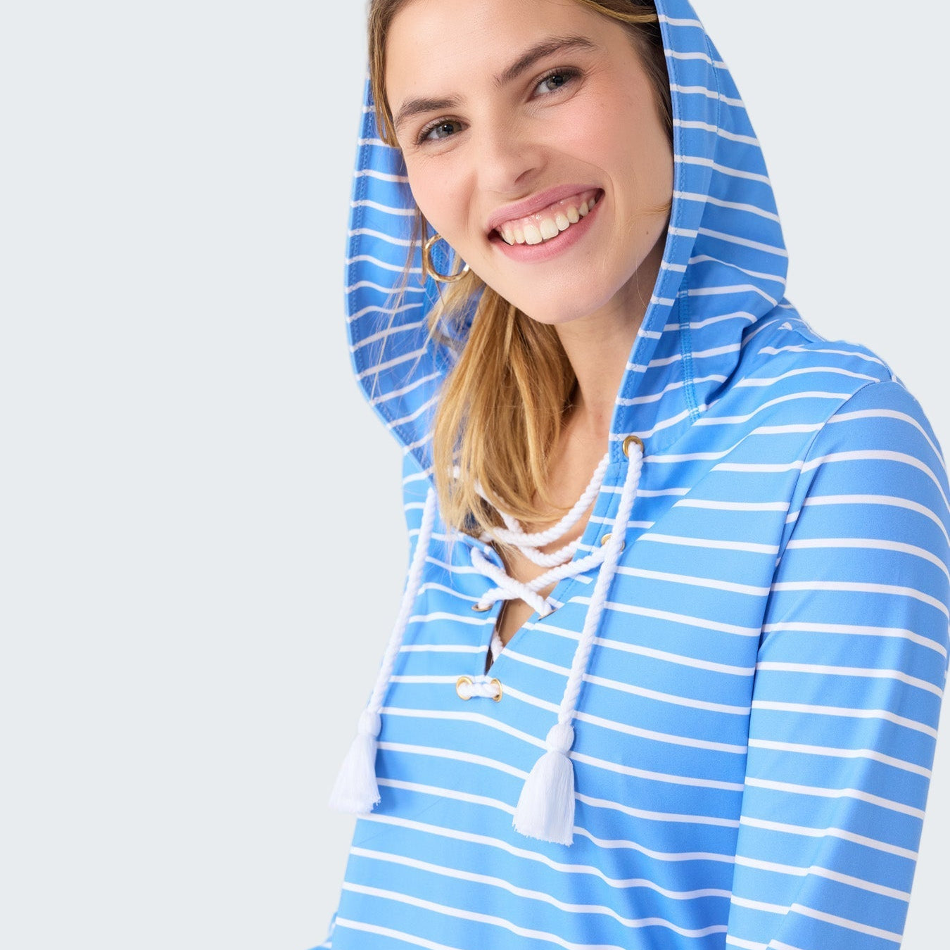 Woman wearing a blue and white striped hoodie on a plain background