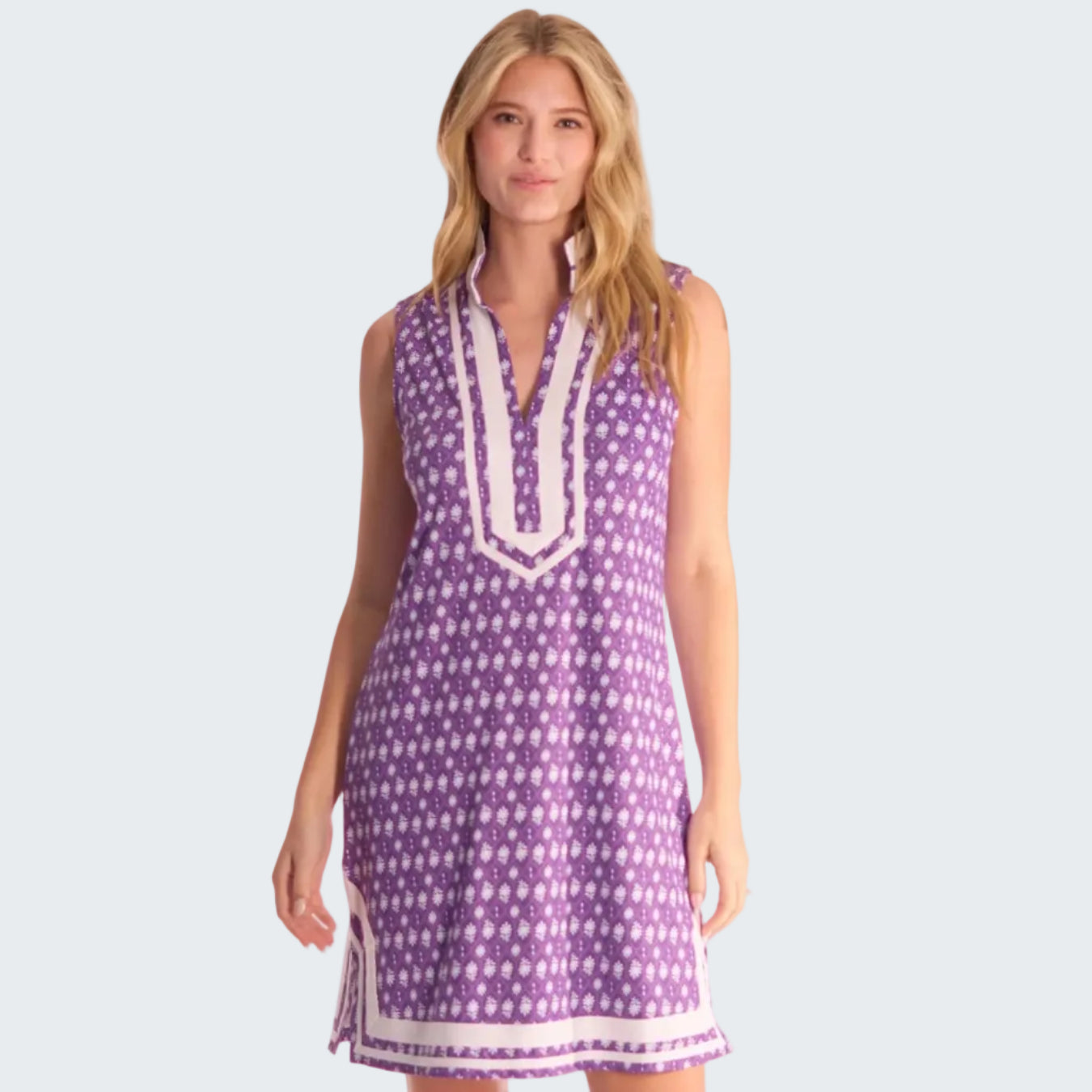 Woman wearing a purple patterned dress with white trim on a white background
