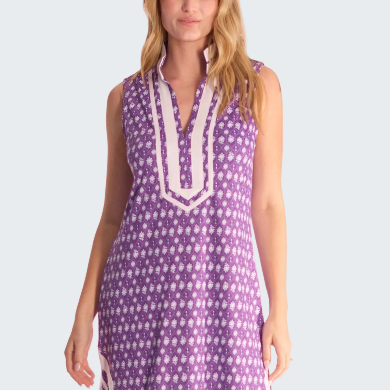 Woman wearing a purple patterned dress with white trim on a white background