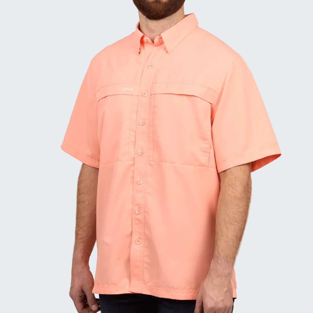 Man wearing a peach-colored short-sleeve shirt on a white background