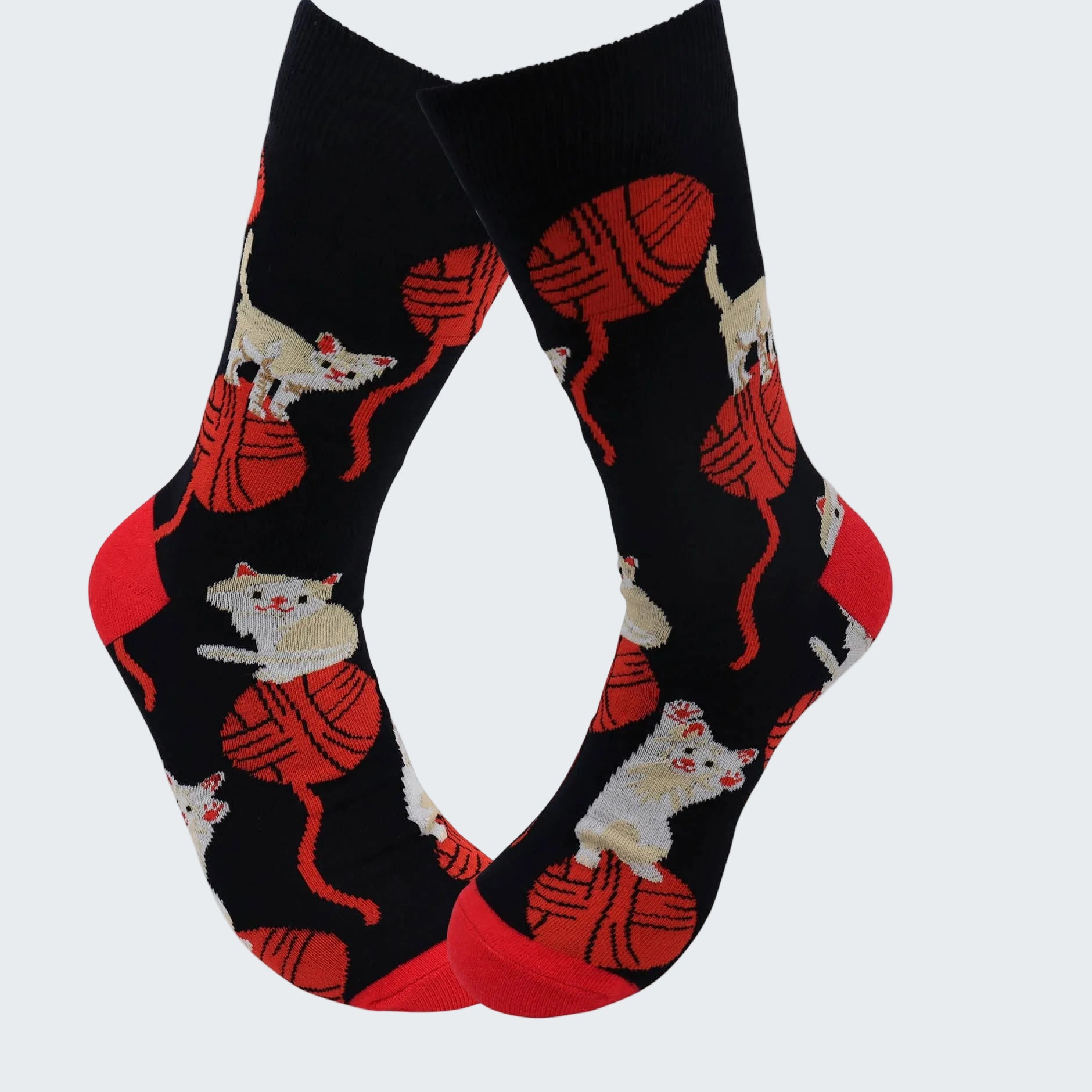 Black socks with red yarn and white cat pattern on a white background