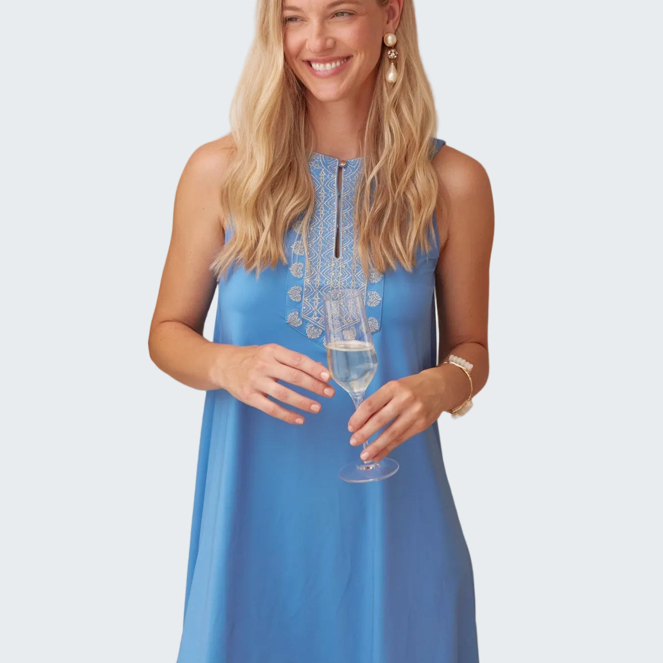 Woman in a blue dress holding a glass of water next to a plant
