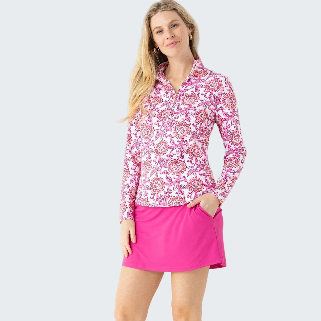 Woman wearing a pink floral long-sleeve top and pink skirt against a white background