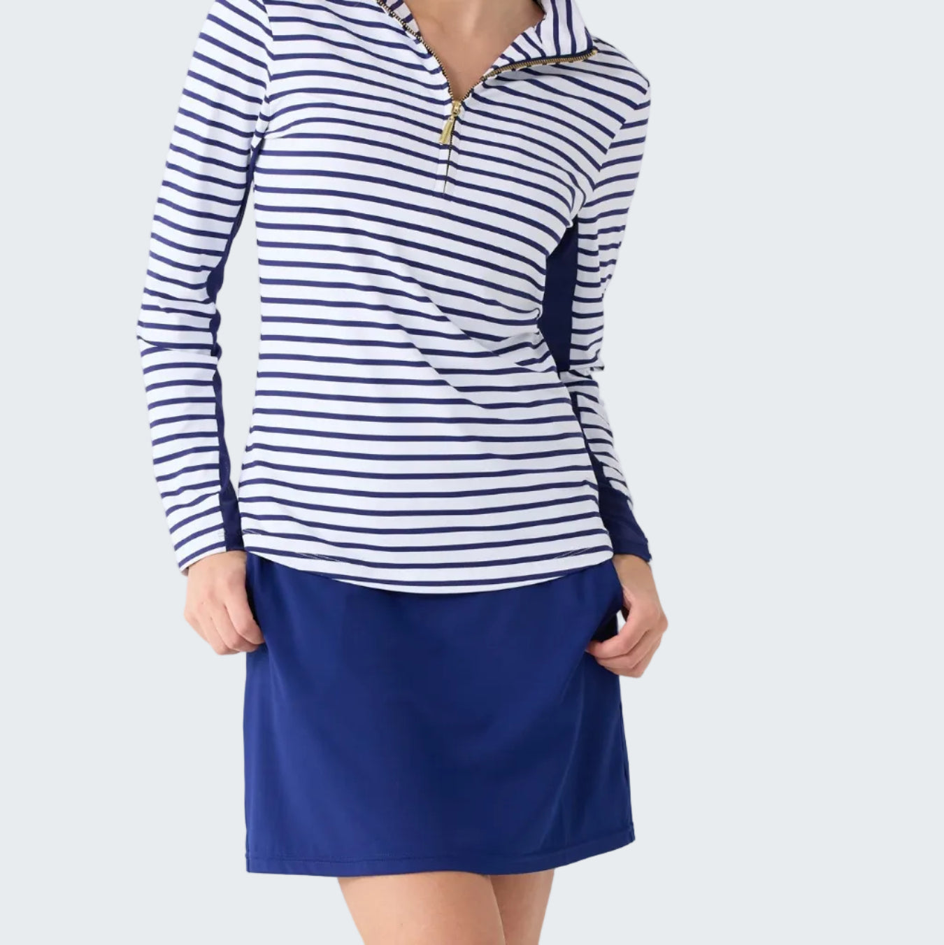 Woman wearing a striped long-sleeve top and blue skirt on a white background