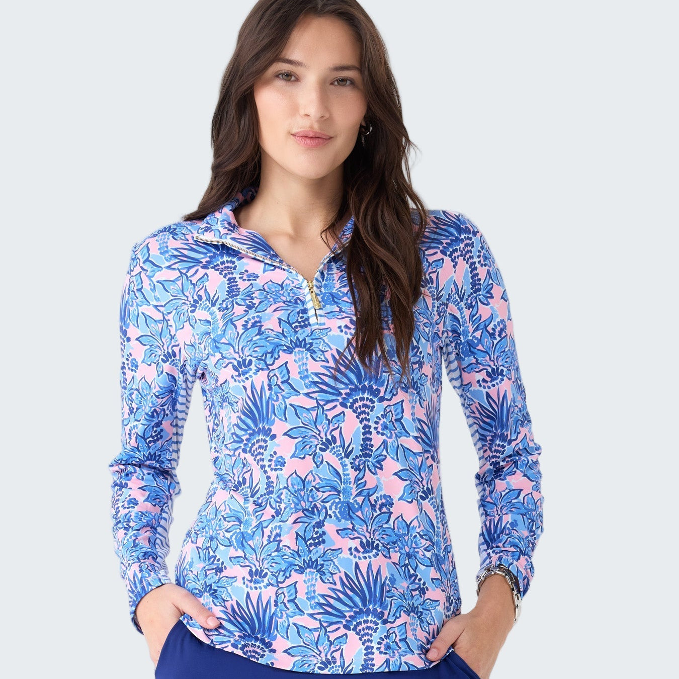 Woman wearing a blue and pink floral long-sleeve top and blue skirt on a white background