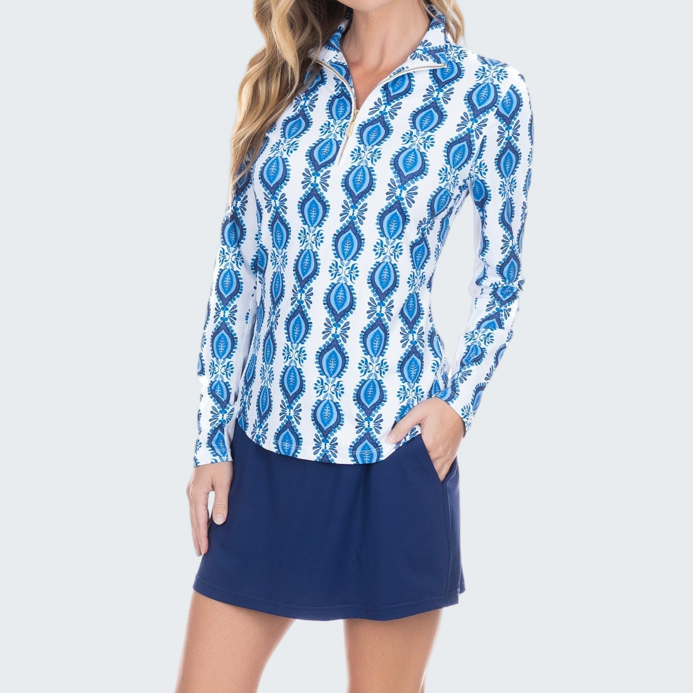 Woman wearing a blue and white patterned shirt with a navy skirt on a white background