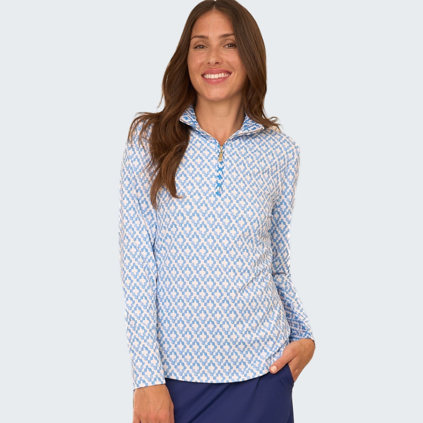 Woman wearing a blue and white patterned long-sleeve shirt with a navy skirt on a white background