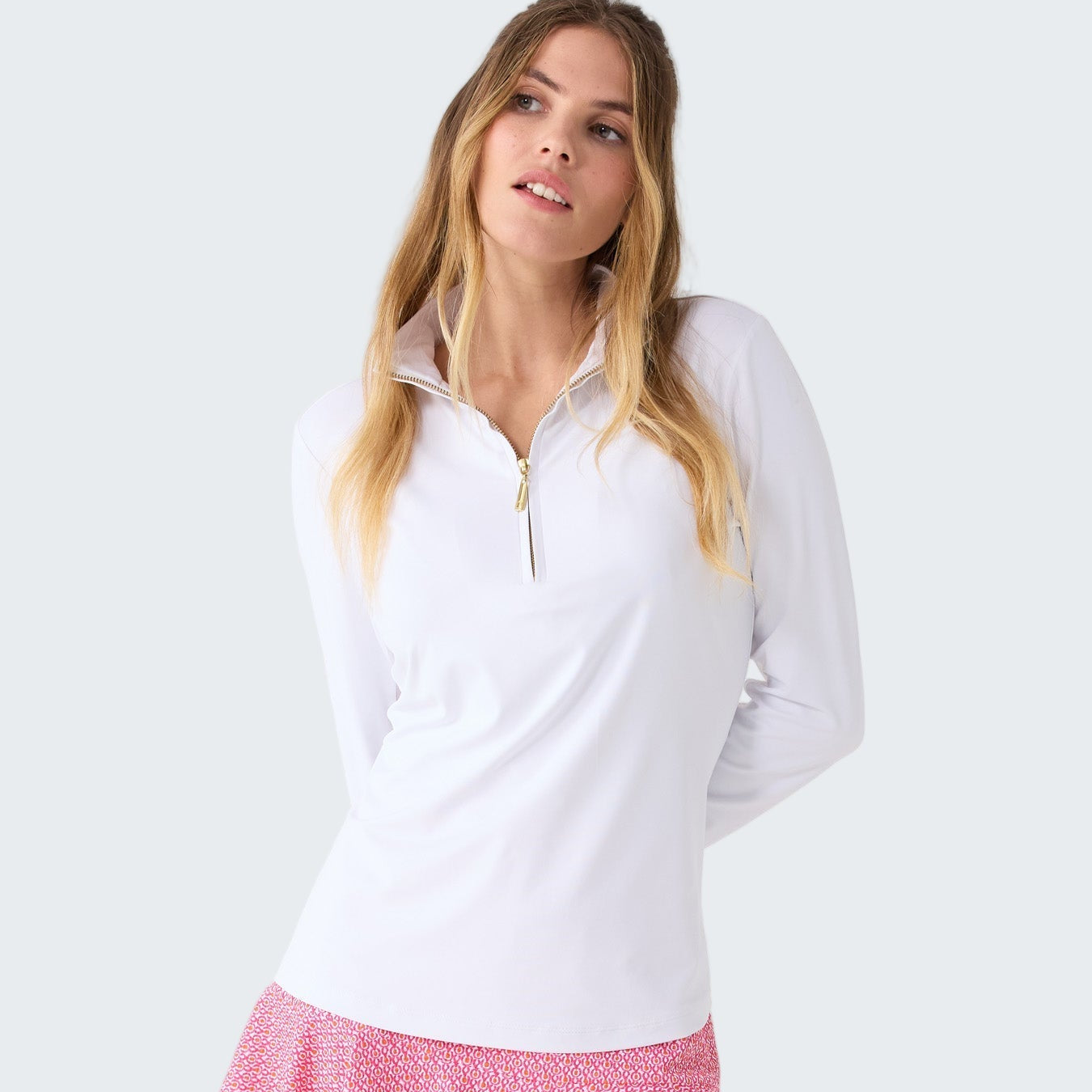 Woman wearing a white long-sleeve top and pink skirt on a white background