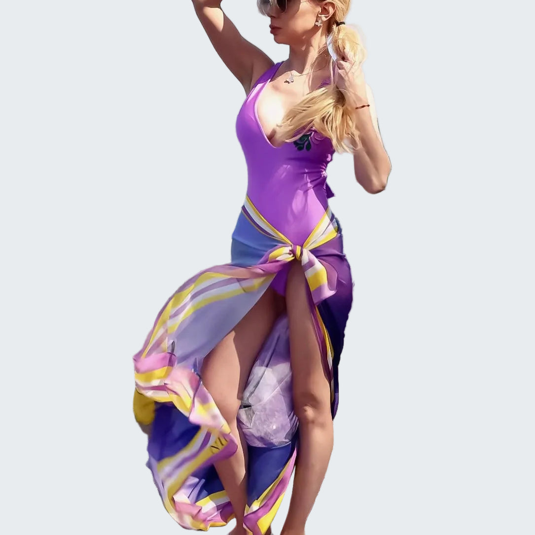 Woman in a colorful dress standing on rocks by the ocean