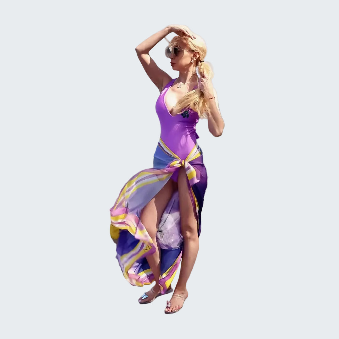 Woman in a colorful dress standing on rocks by the ocean
