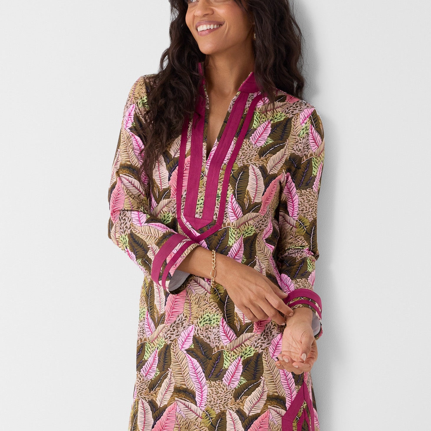 Woman wearing a patterned dress with pink accents on a white background