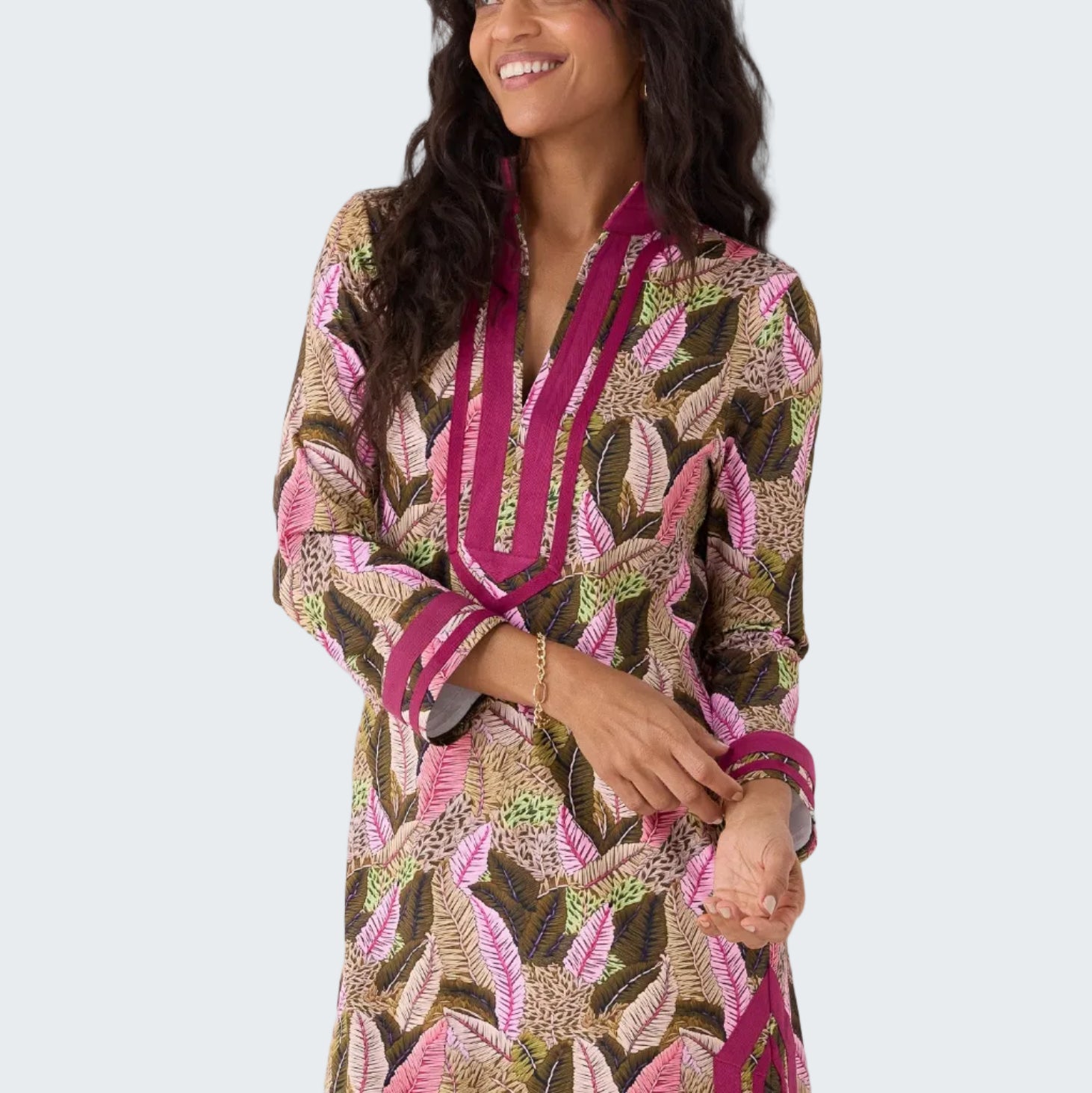 Woman wearing a patterned dress with pink accents on a white background