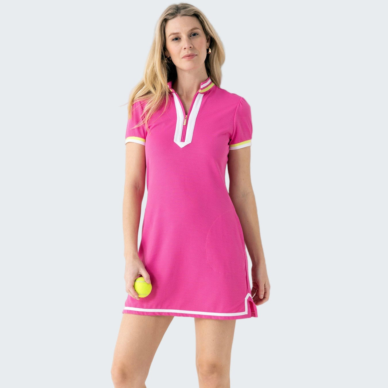Woman wearing a pink dress with white trim, standing against a white background