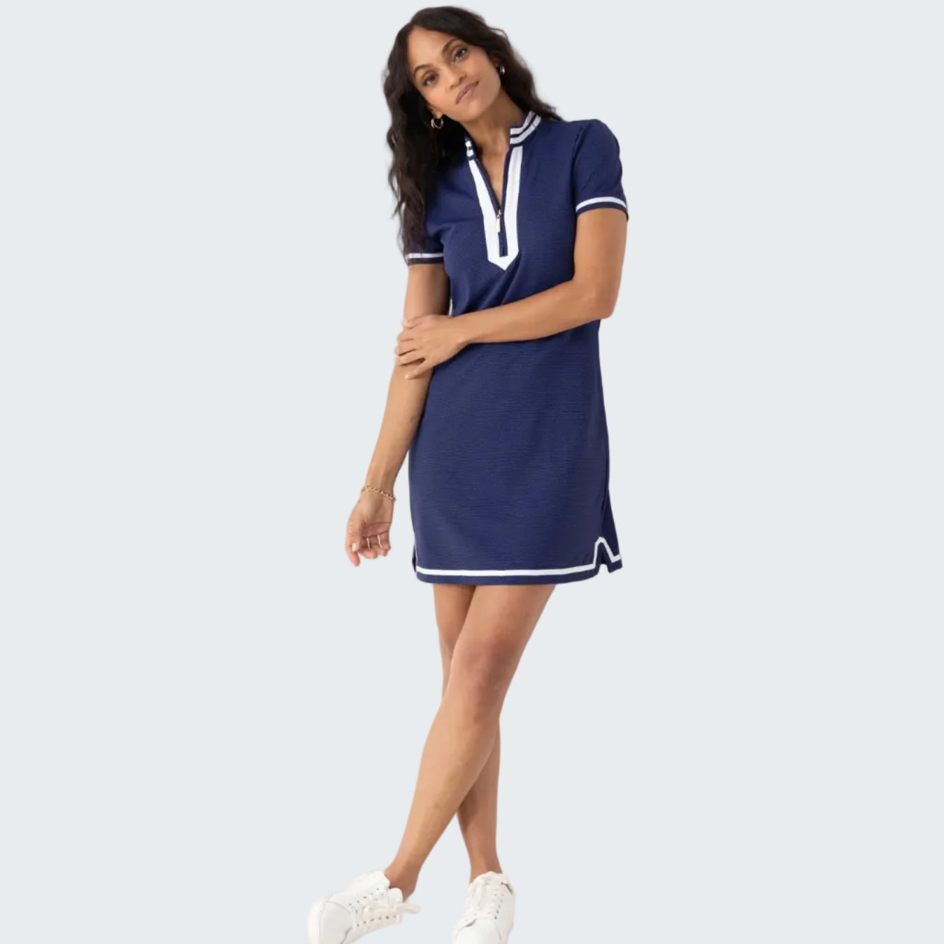 Woman wearing a navy dress with white accents against a white background
