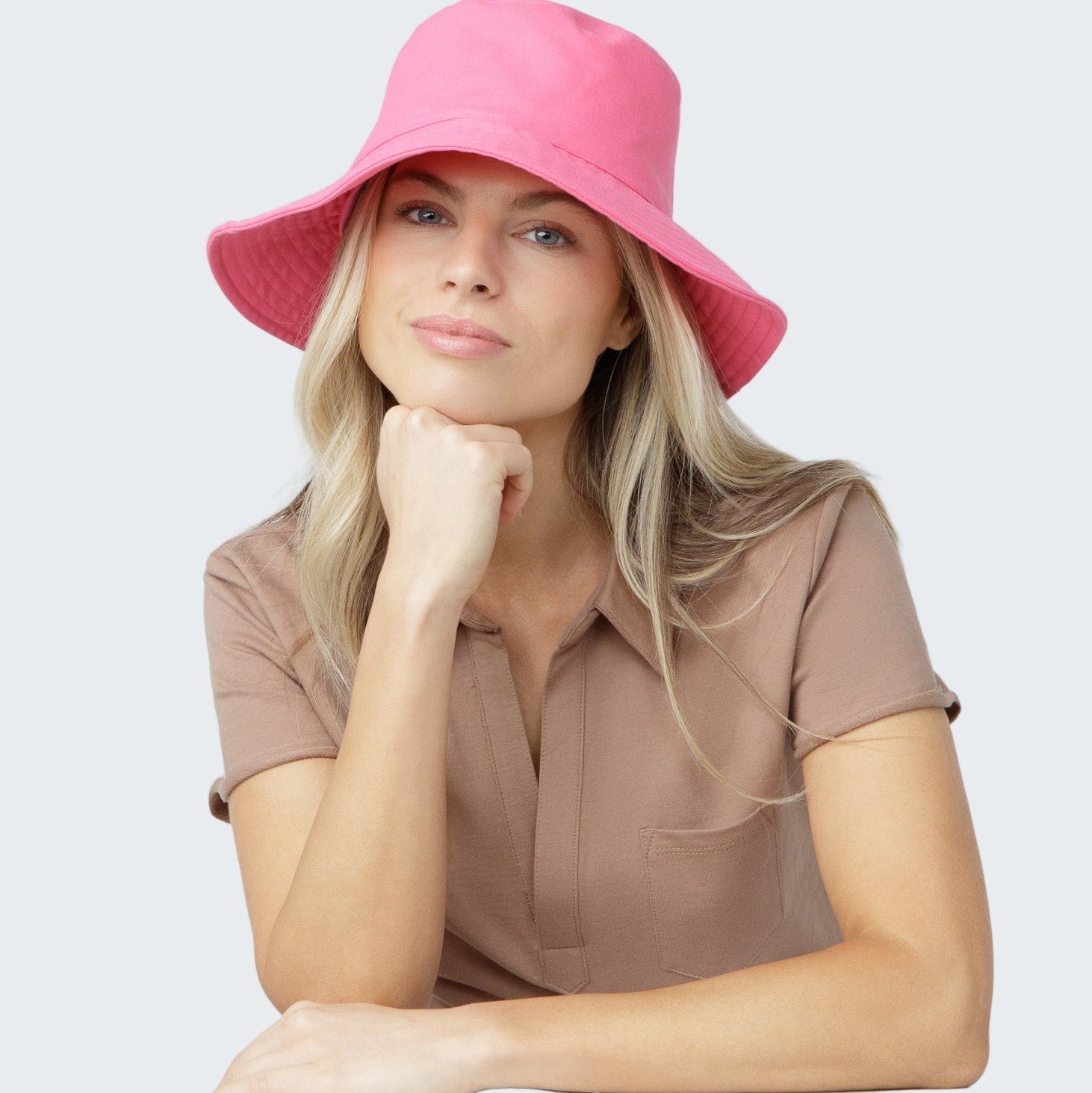 Woman wearing a pink bucket hat against a plain background
